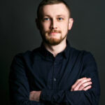 Mateusz Zieliński dark blonde bearded man crosses his hands on chest posing in black shirt